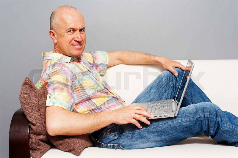 Image of 'elderly man with laptop on sofa'