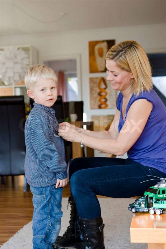 A mother helping his son to change clothes, stock photo