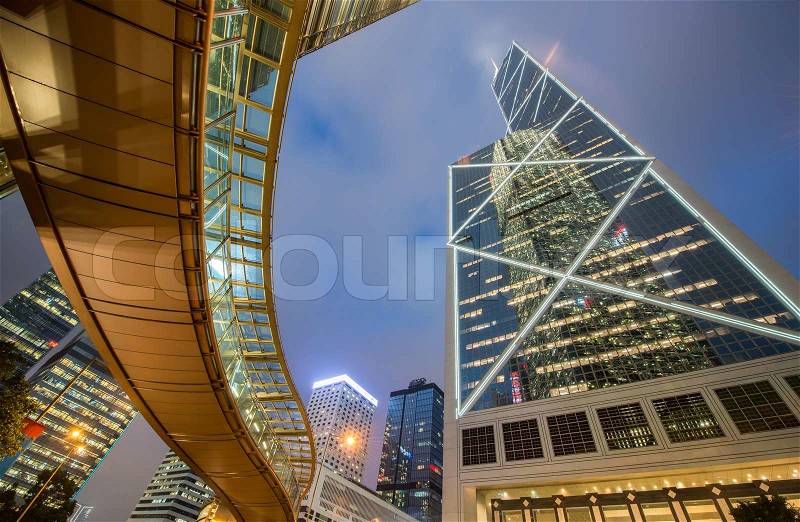 Hong Kong by night. Pedestrian passage over street level and surrounding majestic skyscrapers of downtown. Wide angle view, stock photo