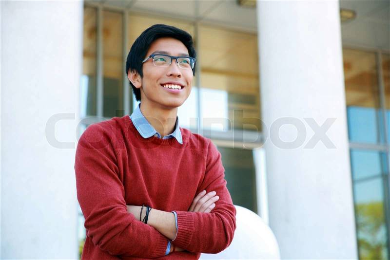 Portrait of a young happy asian man with arms folded looking up, stock photo