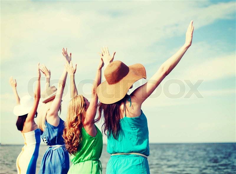 Summer holidays and vacation - girls with hands up on the beach, stock photo