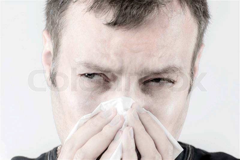 Portrait of a ill man who is sneezing in a tissue, stock photo