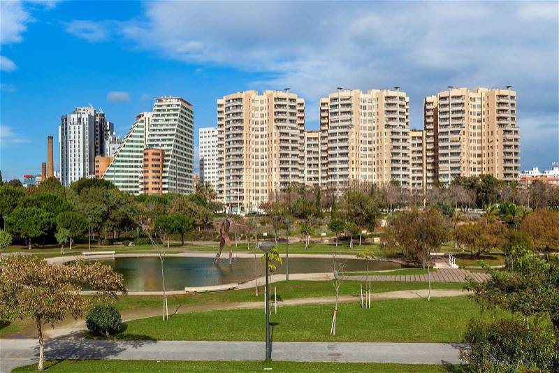 City park with small pond, green lawns and walkways and modern residential buildings on background in Valencia, Spain, stock photo