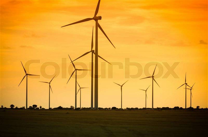 Backlit view of a group of mills for electric power generation, stock photo