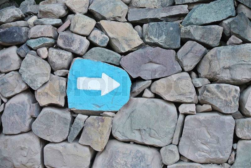Painted signal pointing arrow over a rock wall, stock photo