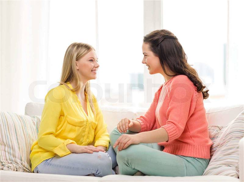 Friendship and happiness concept - two girlfriends having a talk at home, stock photo
