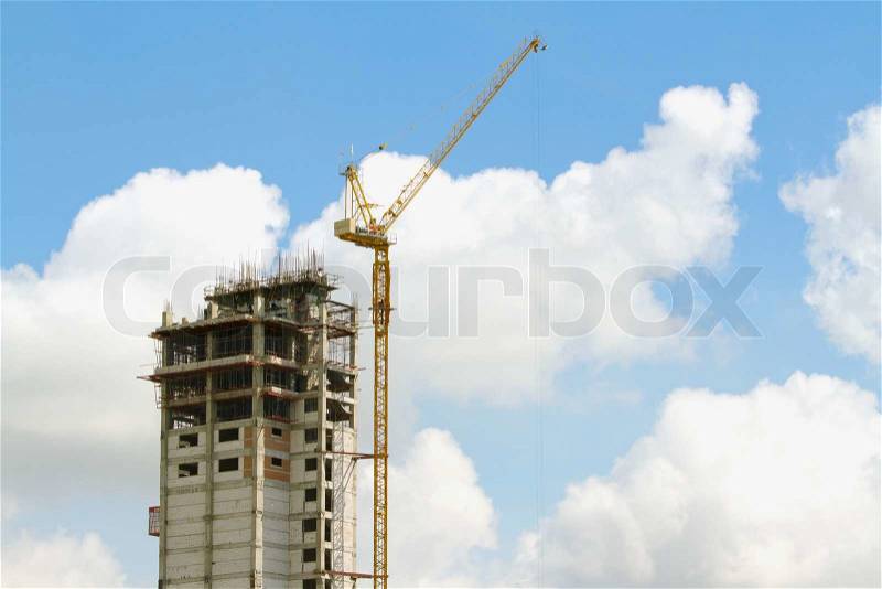 Working cranes inside with tall buildings under construction under a blue sky, stock photo