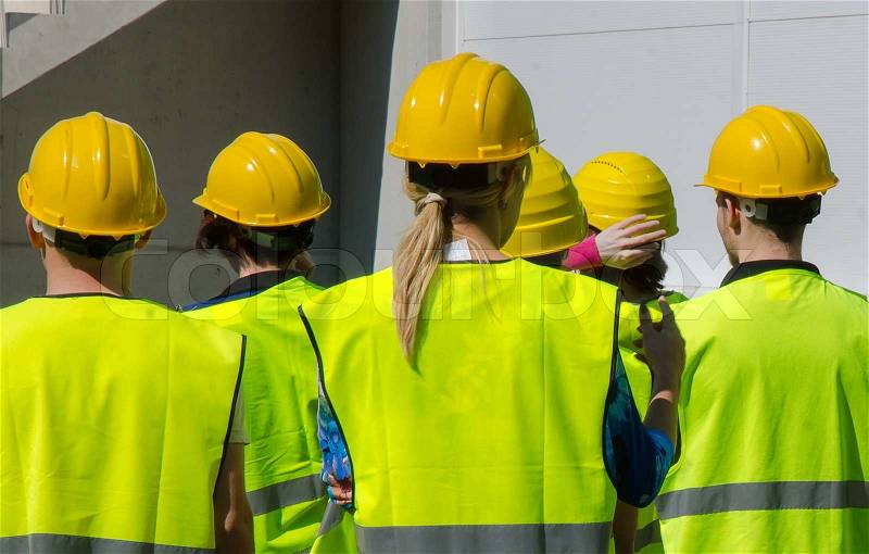 Group of workers in hardhats. View from the back, stock photo