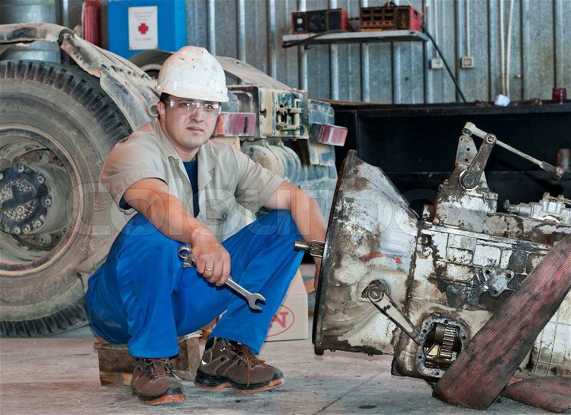 Worker in protective clothes repairs the automobile mechanism, stock photo