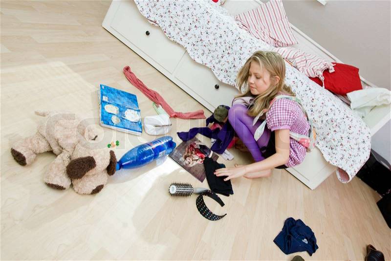 A teenage girl tidying up her messy bedroom, stock photo