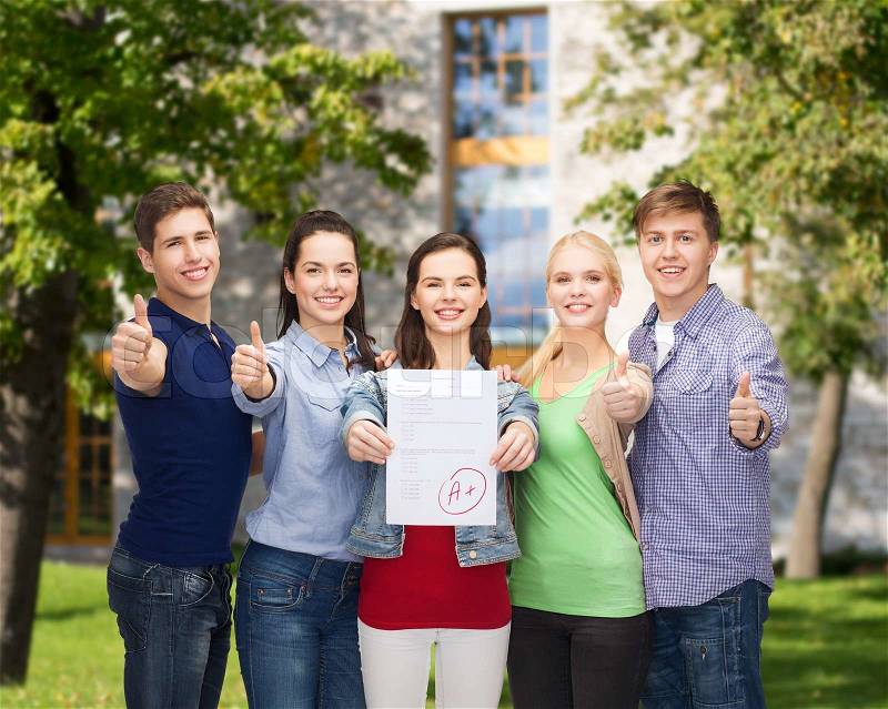 Education and people concept - group of smiling students standing and showing test and thumbs up, stock photo