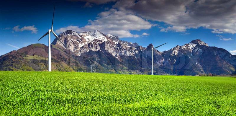Electric wind turbines in the field of winter wheat in the Alps, near the village of Les Moras, Pellafol, France, stock photo