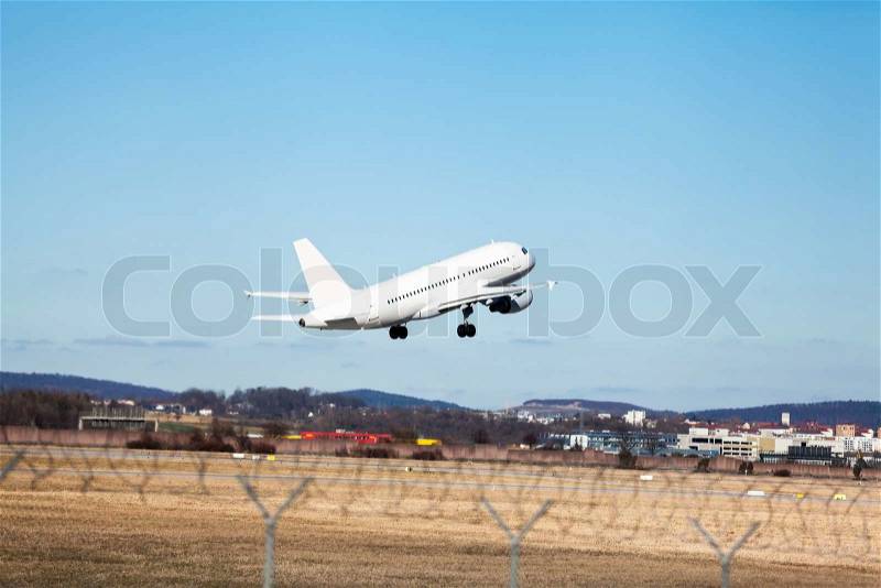 Passenger airliner taking off at an airport lifting clear of the runway in front of the terminal buildings, side view, stock photo