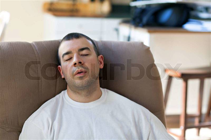 Lazy or overtired man sleeping on the couch in the seated position. Shallow depth of field, stock photo