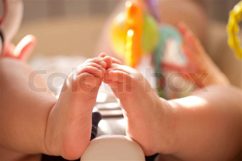 Baby feet close up. Kid playing with toys in the baby chair, stock photo