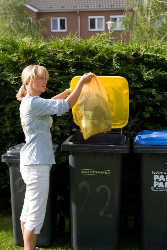 A woman throwing thrash in a recycling bin, stock photo