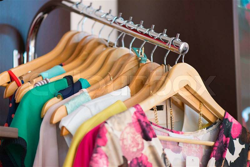 Variety of clothes hanging on rack in boutique, stock photo