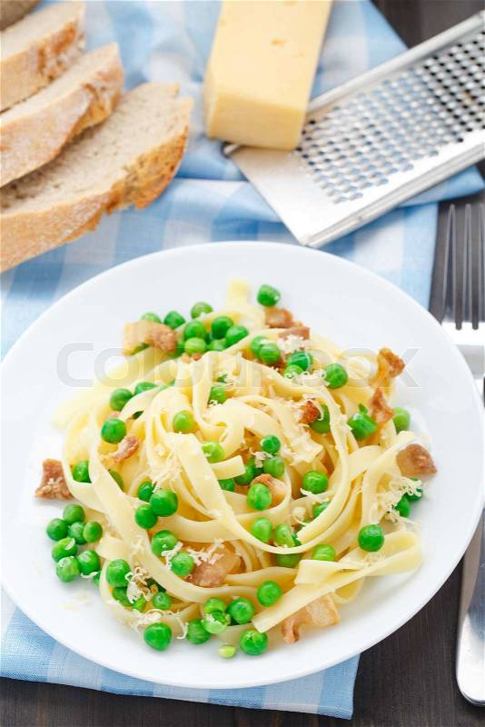 Pasta with peas and bacon on a plate, stock photo