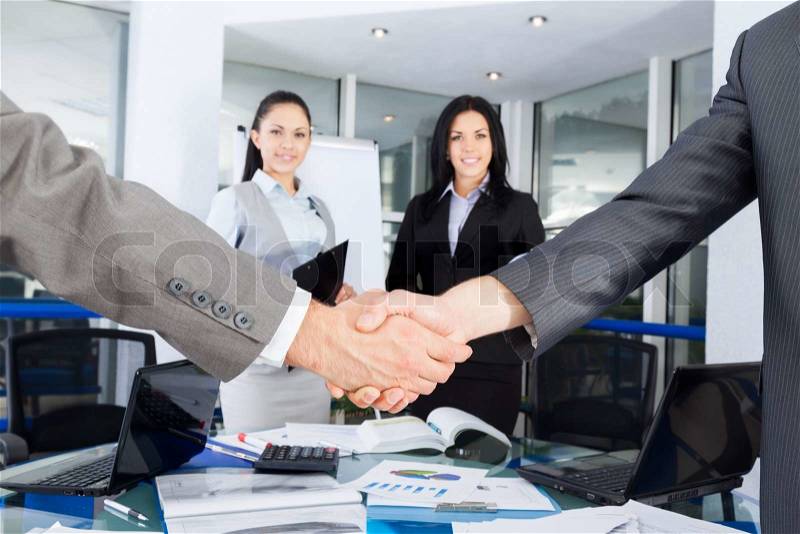 Business handshake with business people on background, colleagues shaking hands during meeting after signing agreement in office, stock photo