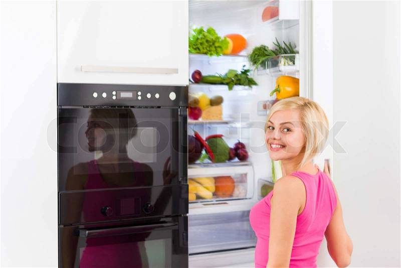 Young woman refrigerator open door, pretty girl smile dieting healthy food vegetables and fruits, modern kitchen, stock photo