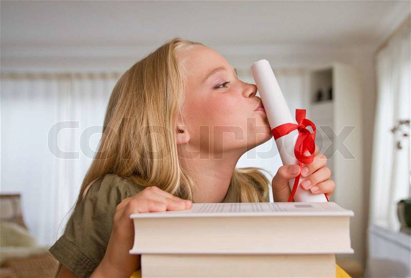 A teenage girl kissing her school certificate, stock photo
