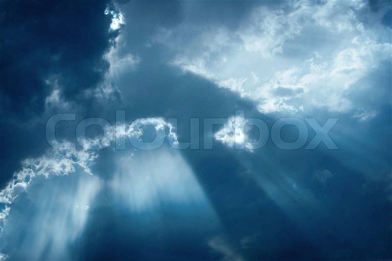 Background meteorological image of rays of sunlight shining through stormy cloud cover in an atmospheric cloudscape, stock photo