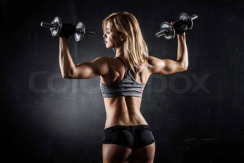 Brutal athletic woman pumping up muscles with dumbbells, stock photo