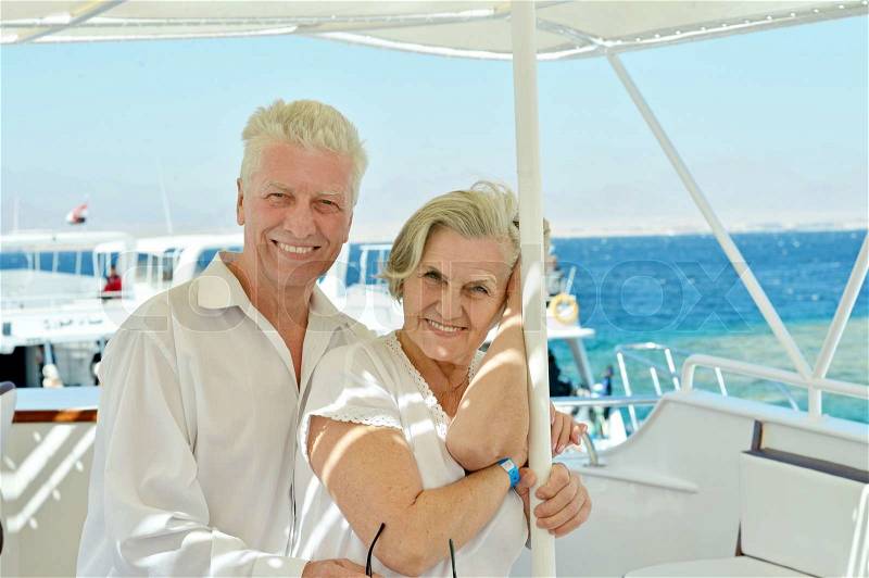 Amusing elderly couple have a ride in a boat on sea, stock photo
