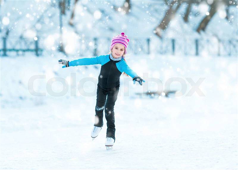 Cheerful cute little girl in thermal suits skating in winter outdoors, stock photo