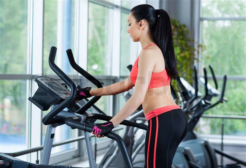 Woman doing legs exercise on stair steppers machine, in gym fitness center, stock photo