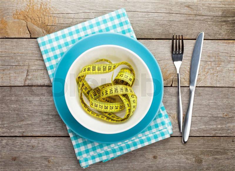 Plate with measure tape, knife and fork. Diet food on wooden table, stock photo