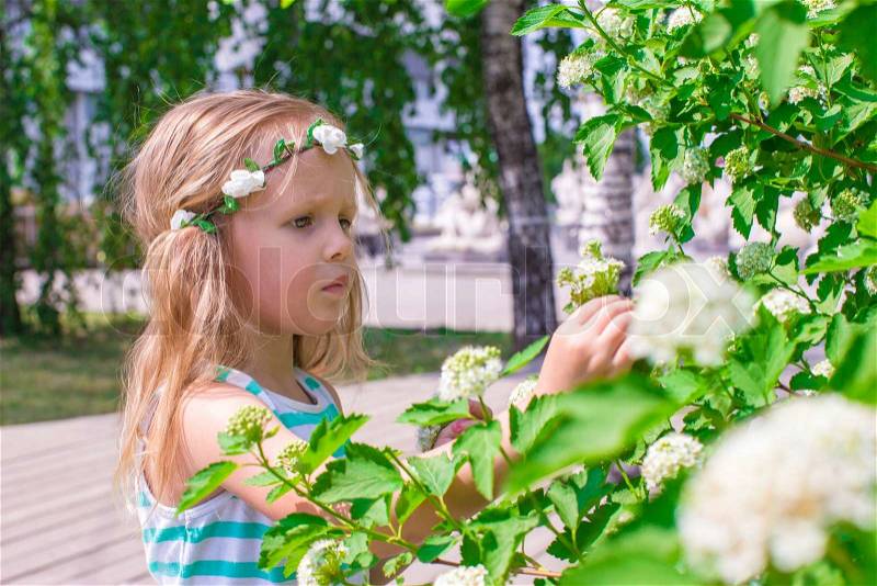 Little adorable girl near white flowers in the garden, stock photo