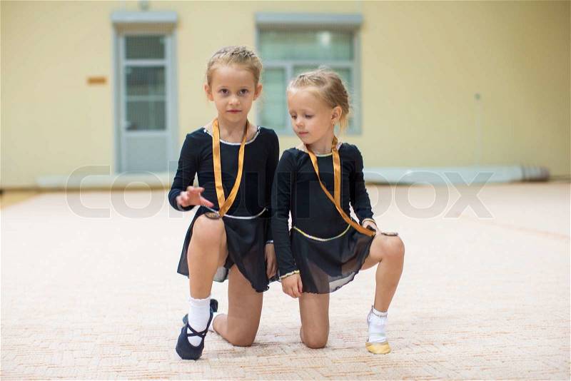 Two little gymnasts in the gym with medals, stock photo