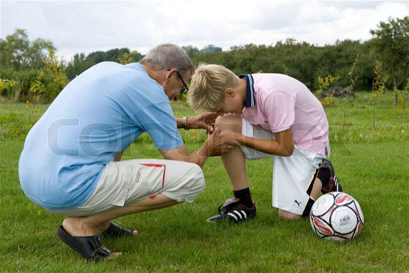 A boy with an injured knee from playing football, stock photo