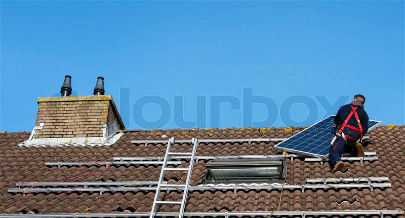 Man putting the solar panel to the metal construction on the roof, stock photo