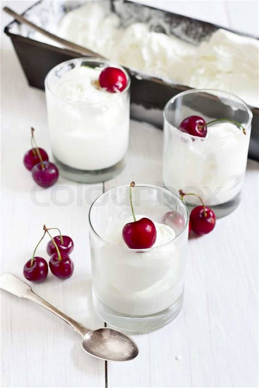 Homemade vanila ice cream in frozen metalic container and glasses with ripe red cherry. Selective focus, stock photo
