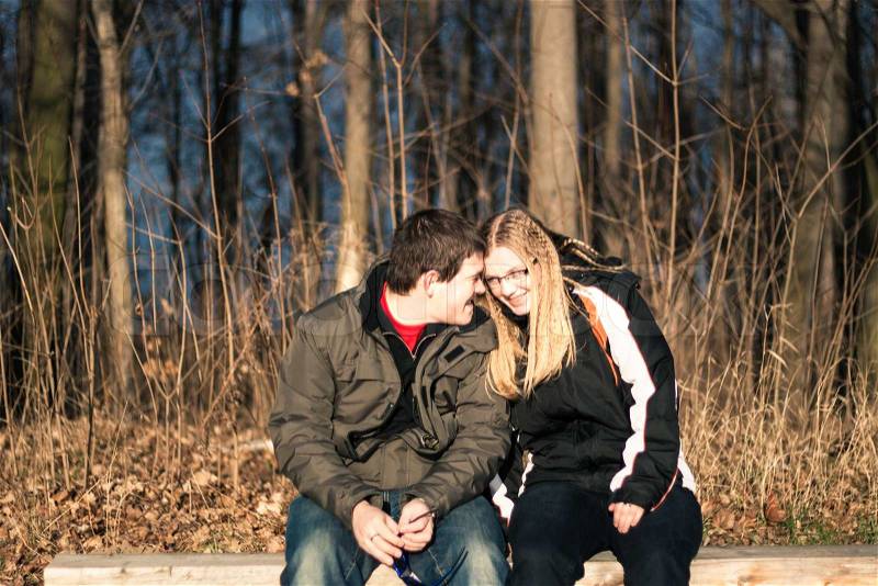Two young happy people sitting on park bench, stock photo