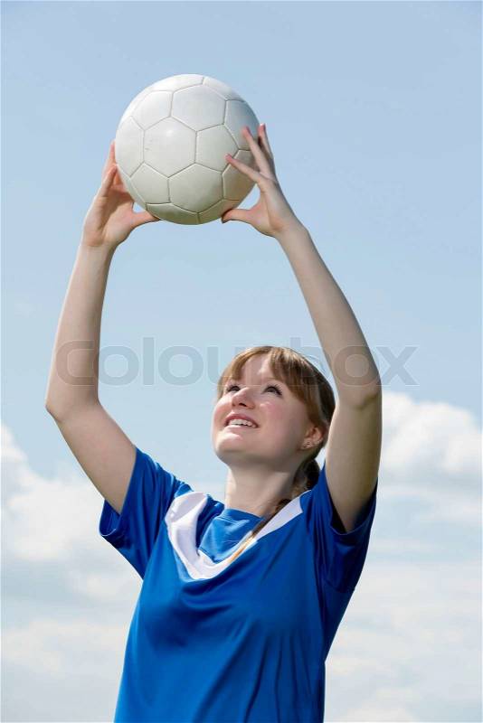 Young woman in blue shirt with soccer ball and blue sky, stock photo