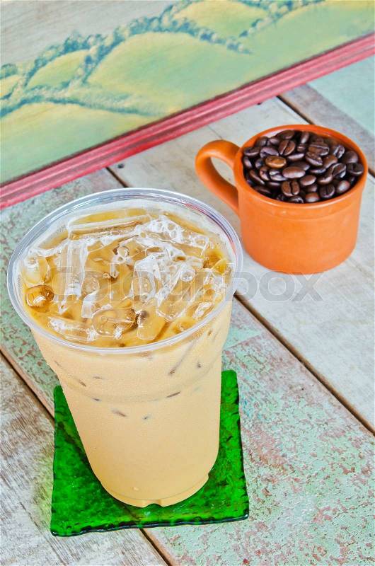 Delicious cold coffee drink with ice on wooden table, stock photo