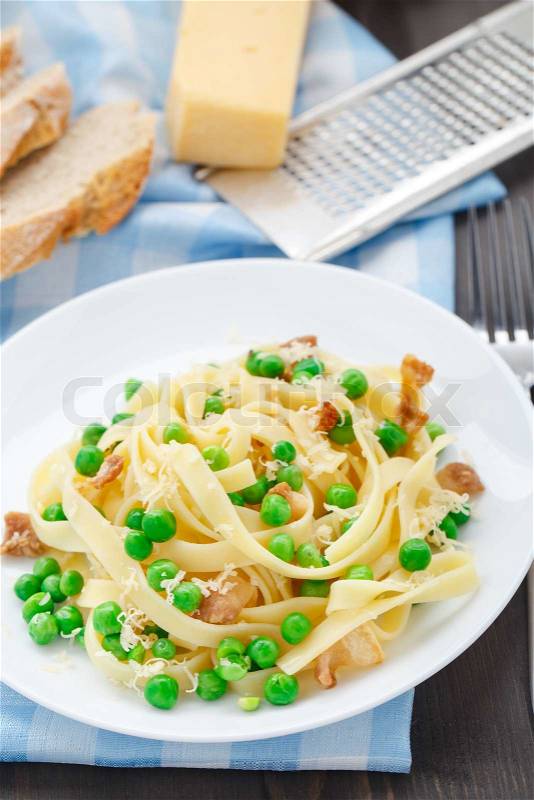 Pasta with peas and bacon on a plate, stock photo