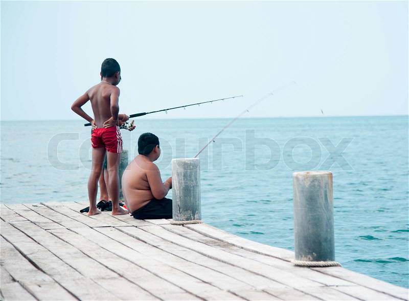Young teenage boy fishing by the sea, stock photo