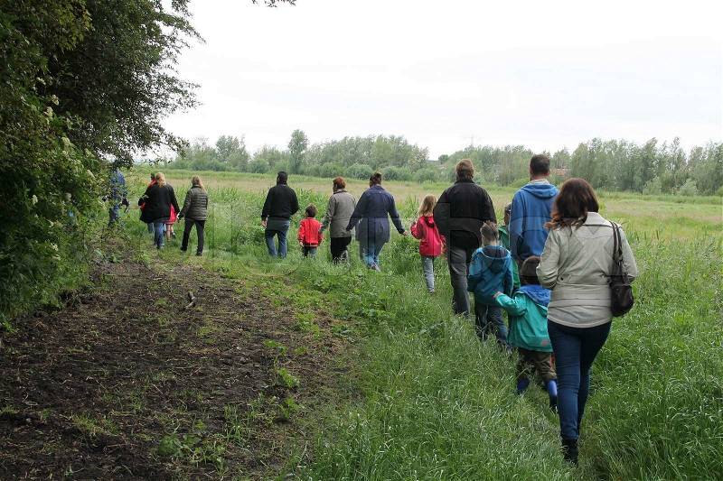 The group with adults and children walk and follow the guide in the forest in wet spring, kids having fun, stock photo