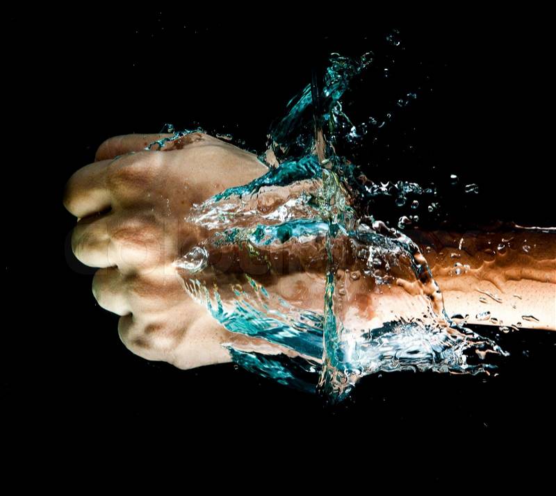 Fist punch into water with big splashes, on a black background, stock photo