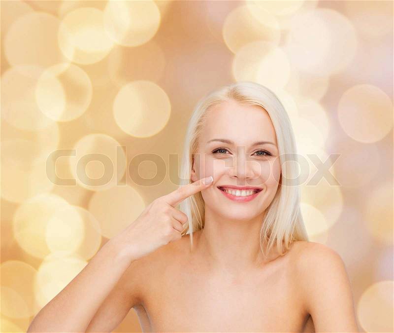 Health and beauty concept - smiling young woman pointing to her nose, stock photo