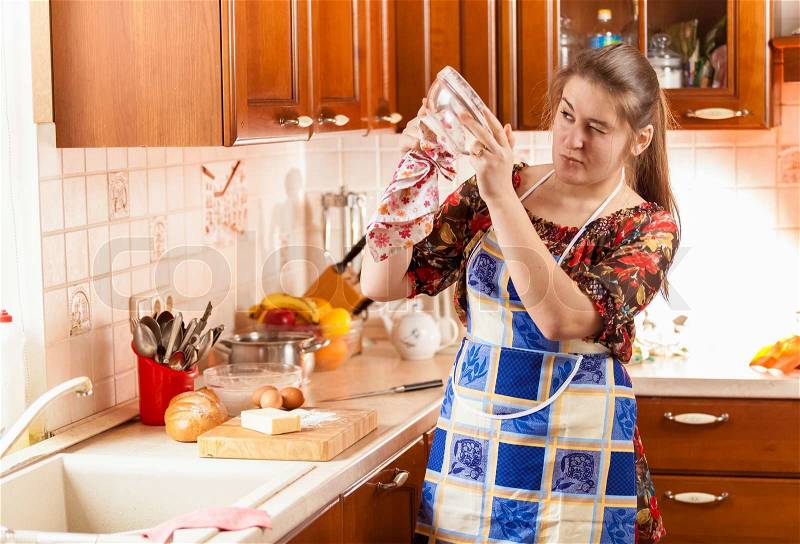 Portrait of housewife checking how clean is the glass bowl, stock photo