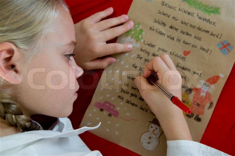 A young girl writing a Christmas song on a piece of paper, stock photo
