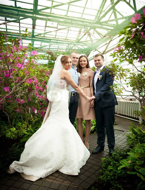 Just married couple posing with friends at greenhouse, stock photo