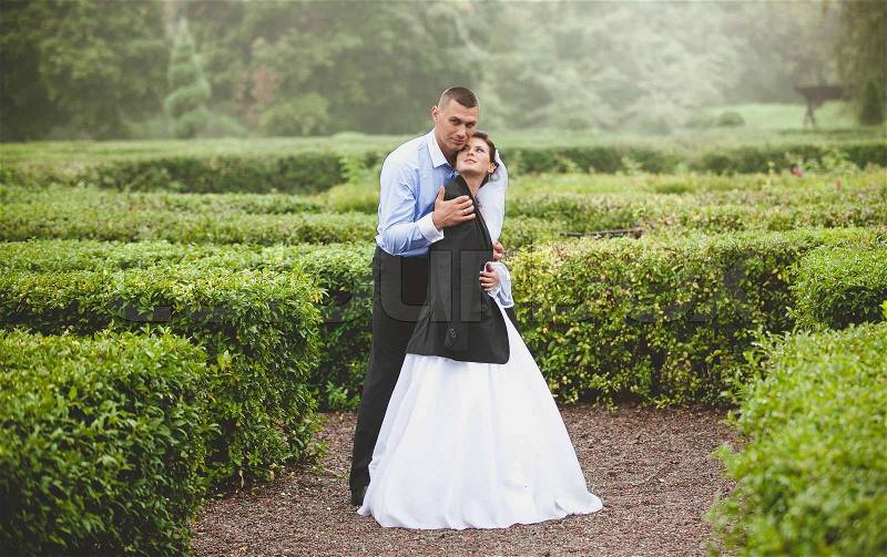 Beautiful bride and groom hugging at garden maze, stock photo