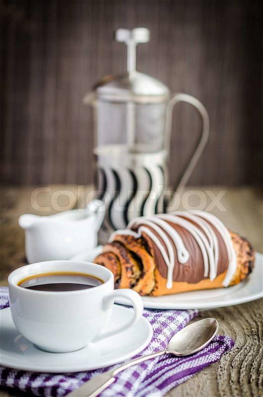 Cup of coffee and poppy bun glazed with ganache, stock photo