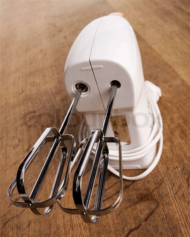 Electric hand mixer on wooden board, stock photo